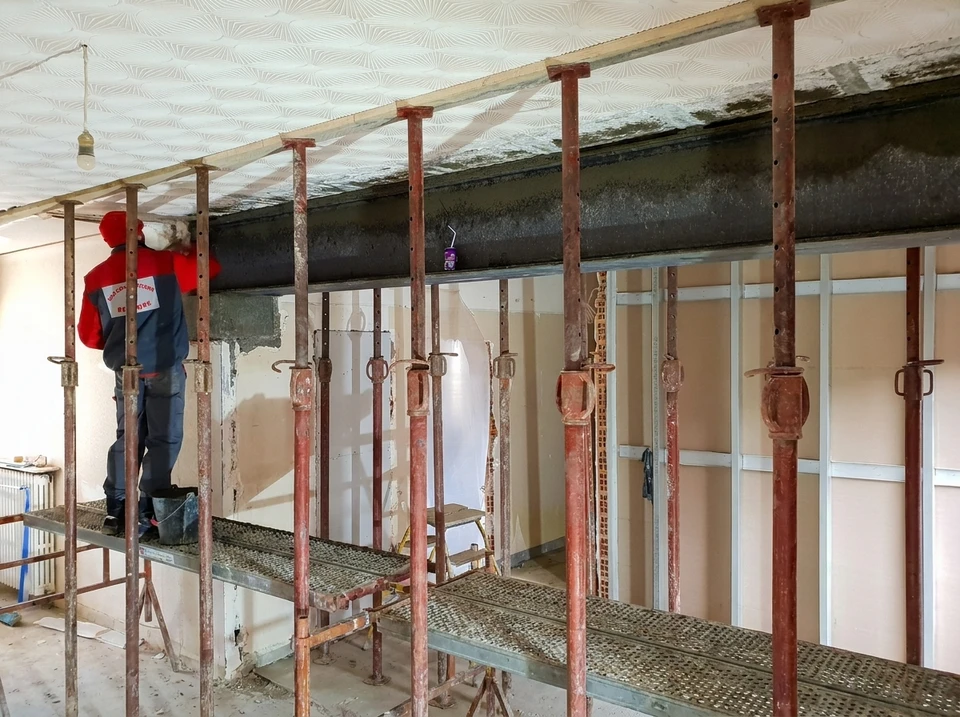 Chantier extérieur de construction, ouvrier installant un ancrage métallique sur poutre béton avec clé à molette