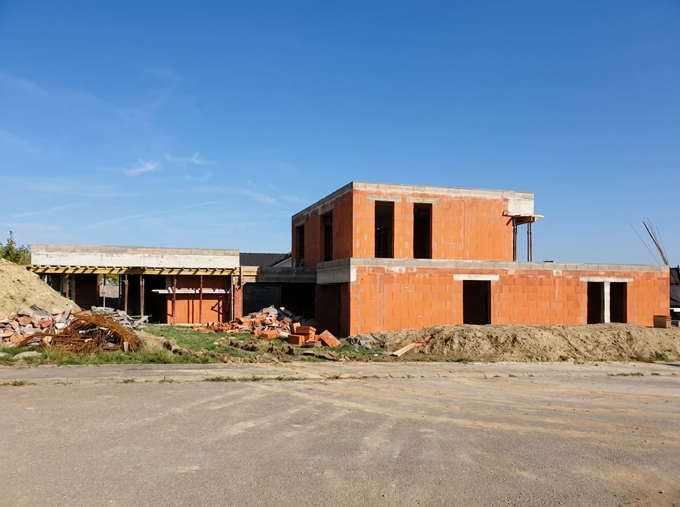 Chantier extérieur avec ouvrier en salopette bleue lissant une dalle de béton fraîchement coulée à l'aide d'une taloche
