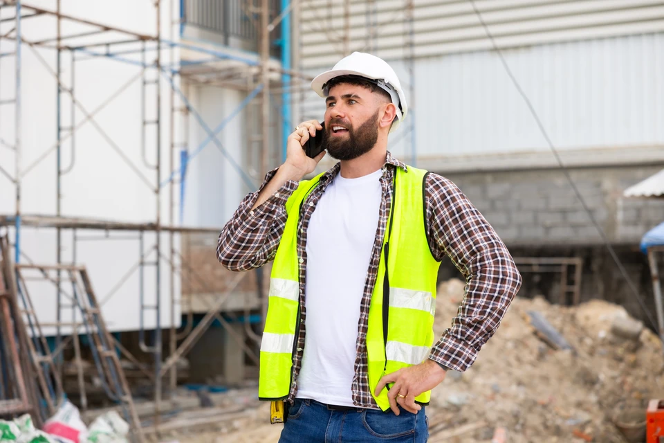 Chantier de construction intérieur avec deux professionnels en casques de sécurité jaune et blanc consultant des plans architecturaux