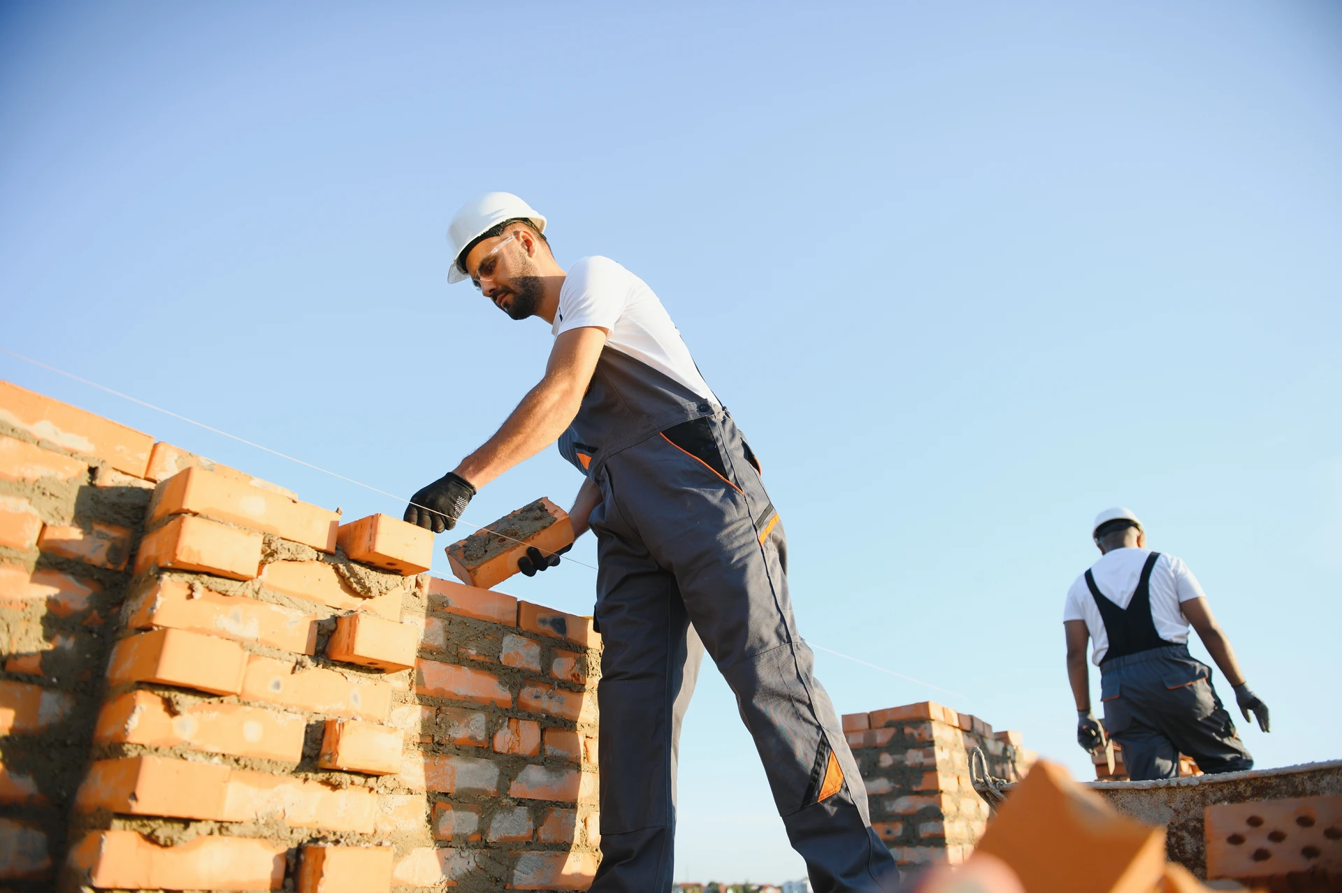Chantier de construction extérieur avec ouvriers installant une poutre métallique sur structure échafaudage