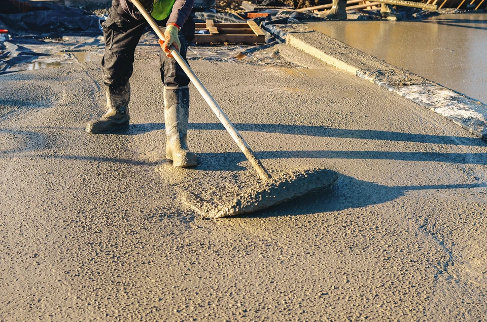 Chantier de construction en extérieur avec ouvriers en équipements de protection individuelle travaillant sur une dalle béton